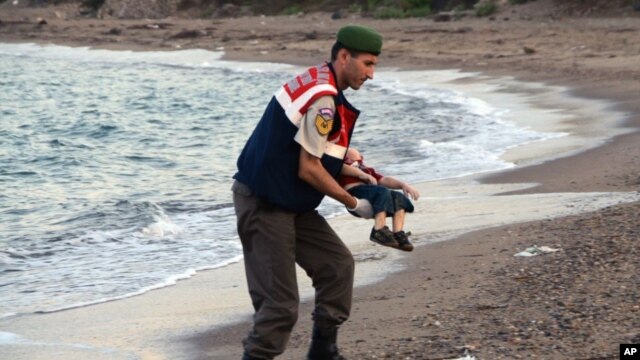 Sĩ quan cảnh sát bế thi thể bé Aylan 3 tuổi bị chết đuối và trôi dạt vào bờ biển Thổ Nhĩ Kỳ.