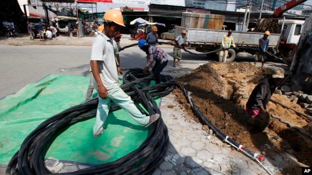 FILE - Cambodian construction workers move the electric wire for connecting at a construction site in Phnom Penh, Cambodia, Dec. 4, 2014. 