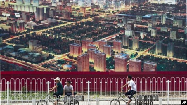 人们骑自行车经过北京一座广告牌,广告牌显示了北京中央商务区的景象(资料照片)