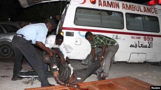Somali policemen move a victim after a suicide bomb attack at Village restaurant in Mogadishu, September 20, 2012.