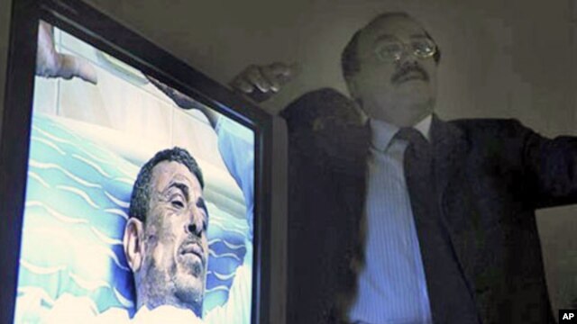 A monitor displays video of 48-year old Abdou Abdel-Monaam Hamadah, at a Cairo hospital, as unidentified plastic surgeon, right, talks about the medical case.  Hamadah apparently set himself on fire Monday outside the country's parliament in a personal pr