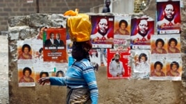 A woman walks past a wall covered with campaign posters on a street in Kenya's capital Nairobi March 3, 2013.