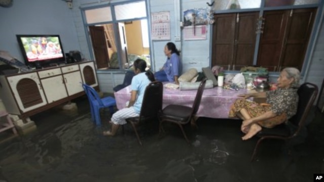 Family members watch TV lifted to avoid flooding at their home in Bangkok, Thailand, October 3, 2011.