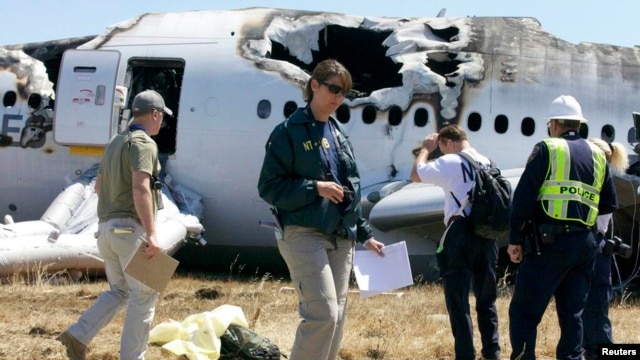2013年7月7日，美国国家交通安全委员会（NTSB）调查人员站在旧金山飞机场韩亚航空公司客机失事的现场。