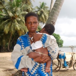 An Ivorian boy holds his baby brother at the Koblakan river crossing in Liberia