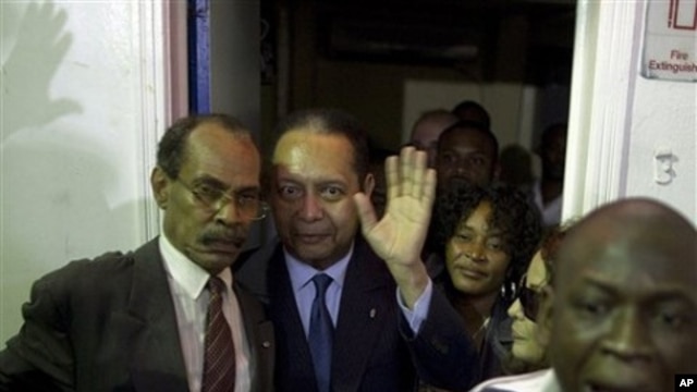 Haiti's former dictator Jean-Claude "Baby-Doc" Duvalier, center, waves to the media upon his arrival at the Toussaint Louverture international airport in Port-au-Prince, Haiti, 16 Jan. 2011.