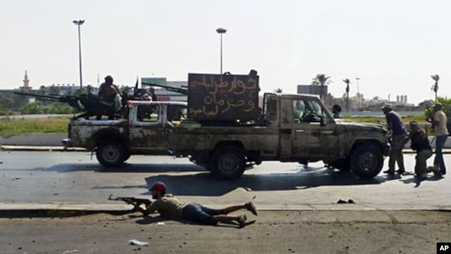 Libyan rebel fighters return fire during an attack by pro-Gadhafi forces after rebels seized a Gadhafi army women's officer training center in Tripoli August 22, 2011