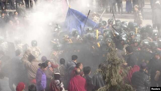 In this handout photo released by The International Campaign for Tibet (ICT) on December 7, 2012, paramilitary policemen are seen closing in on Dorje Rinchen's body after his self-immolation, in Xiahe,  Gansu province, October 23, 2012. 