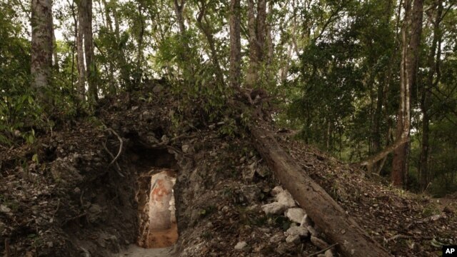 The painted figure of a man — possibly a scribe who once lived in the house built by the ancient Maya —  is illuminated through a doorway to the dwelling, in northeastern Guatemala. (Tyrone Turner © 2012 National Geographic) 