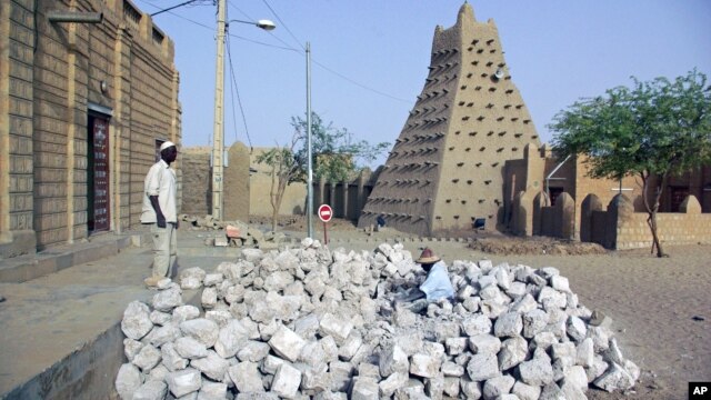 In this May 1, 2012 photo, men work alongside one of Timbuktu's historic mud mosques in Mali. 