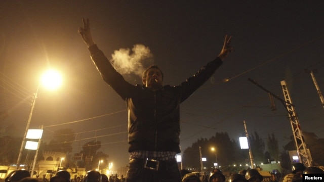 An anti-Morsi protester smokes a cigarette and and gestures in front of members of the Republican Guard blocking a road to the presidential palace in Cairo, Egypt, December 6, 2012. 
