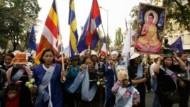 Villagers from Boeung Kak lake march through the main street, wearing a portrait of detained Yoam Bopha, Buddhism, poster and flags to mark the World Women's Day in Phnom Penh, Cambodia, Friday, March. 8, 2013. Bopha was arrested by local authorities after her protest over compensation for her loss of her house due to a new luxury housing development. The protesters demanded the release of Bopha. (AP Photo/Heng Sinith)