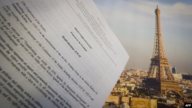 An illustration picture taken on Dec. 10, 2015 in Paris shows a draft for the outcome of the COP21 United Nations conference on climate change next to a picture of the Eiffel Tower.