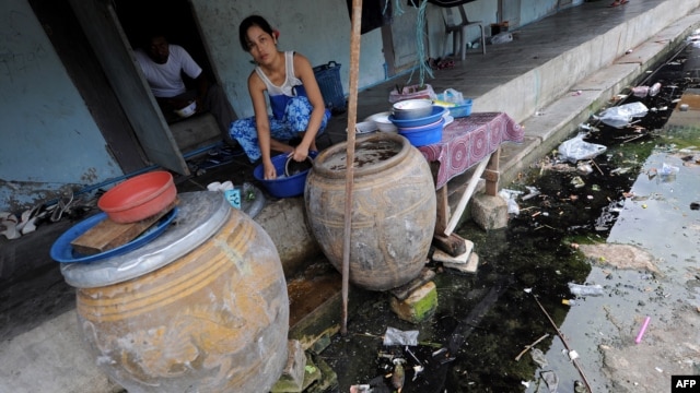 A Burmese migrant washes dishes outside her room at an apartment building housing Burmese migrant workers in Mahachai, an industrial area south of Bangkok, August 25, 2010.