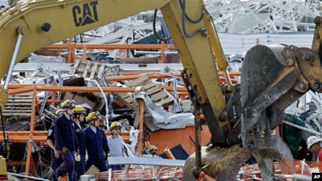 Members of Missouri Task Force One search-and-rescue team stand by as heavy equipment moves debris from a tornado-damaged Home Depot store, in Joplin , Missouri, May 24, 2011
