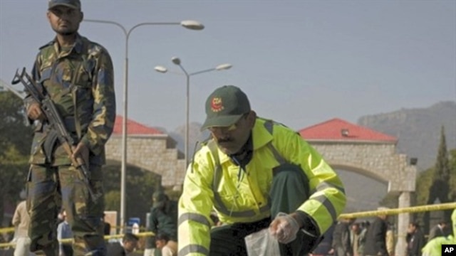 Official picks up pieces of flesh belonging to suicide attacker outside Pakistani naval headquarters in Islamabad, 2 Dec 2009