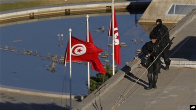 Soldiers stand guard atop a building the center of Tunis, 15 Jan 2011