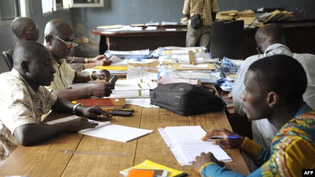 Guinean election officials examine votes at a collation center in the Conakry neighborhood of Ratoma, Oct. 14, 2015. Turnout in Sunday's controversial first round of balloting was estimated at almost 75 percent.