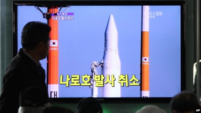 People watch a TV broadcasting a report about the cancellation of a launch of the Korea Space Launch Vehicle-1, at Seoul Railway Station in Seoul, South Korea, November 29, 2012.