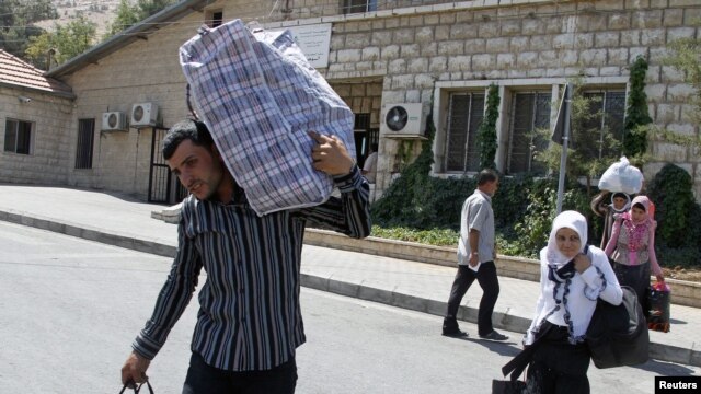 Syrian refugees walk with their belongings on the Lebanese-Syrian border, in al-Masnaa, July 20, 2012