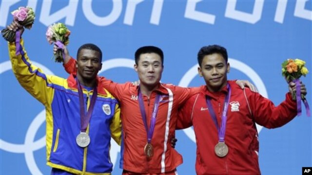 Eko Yuli Irawan yang meraih perunggu (kanan) mengaku masih menderita cedera retak pada tulang keringnya pada saat tampil di Olimpiade, Senin (30/7).