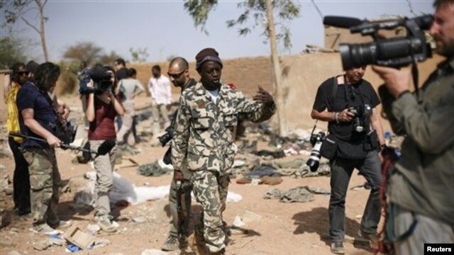Malian soldier gestures at journalists to leave area of a French air strike in Konna, 430 miles north of Bamako, Jan. 26, 2013.