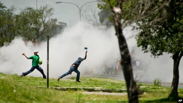 Protesters caught in teargas, hurl stones at police, unseen, during violent clashes in Sasolburg, South Africa, January  22 2013.