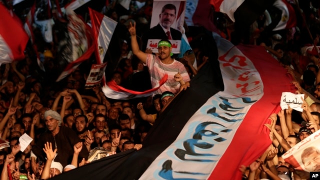 Supporters of Egypt's ousted President Mohammed Morsi hold a large Egyptian national flag as they chant slogans against Defense Minister Gen. Abdel-Fattah el-Sissi, in Cairo, Aug. 2, 2013. 