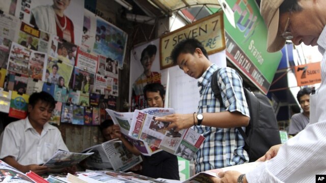 Customers buy local weekly journals at a roadside shop in Rangoon, Burma, Aug. 20, 2012. 