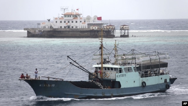 In this photo taken on July 20, 2012, a fishing boat sails past the Meiji reef off the island province of Hainan in the South China Sea. China's newest city, on a small, remote island in the South China Sea, is also claimed by Vietnam.