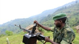 A M23 rebel fighter prepares his machine gun at their defense position in Karambi, eastern Democratic Republic of Congo (DRC) in north Kivu province, near the border with Uganda, July 12, 2012. 