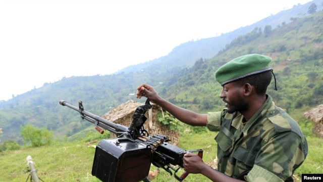 A M23 rebel fighter prepares his machine gun at their defense position in Karambi, eastern Democratic Republic of Congo (DRC) in north Kivu province, near the border with Uganda, July 12, 2012. 