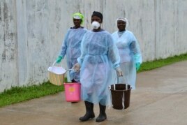 Các nhân viên y tế mang theo những chiếc xô đựng dung dịch khử trùng tại một trung tâm điều trị Ebola mới được xây dựng ở Monrovia, Liberia.