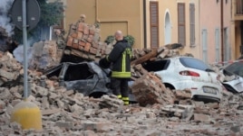 An Italian firefighter stands among rubble and destroyed cars in Modena, Italy, May 20, 2012.