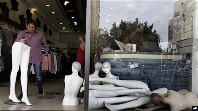 Israeli retailer cleans up after rocket from Gaza Strip lands nearby in Ashdod, March 13, 2012.