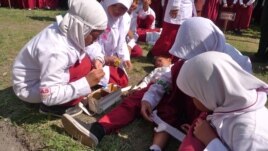 Students trained in first aid assist a classmate during a mock earthquake drill in Central Java, Indonesia, October 22, 2012. (S. Schonhardt/VOA)