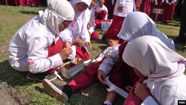 Students trained in first aid assist a classmate during a mock earthquake drill in Central Java, Indonesia, October 22, 2012. (S. Schonhardt/VOA)