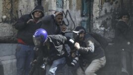 Fotoreporteri se zaklanjaju od kamenica koje su demonstranti u Kairu danas bacali na policiju