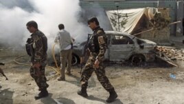 Lực lượng an ninh Afghanistanđi ngang một chiếc xe đang bốc cháy sau khi một nhóm phiến quân xông vào một khu nhà do cơ quan tình báo của Afghanistan sử dụng ở Kabul, ngày 7 tháng 7, 2015.