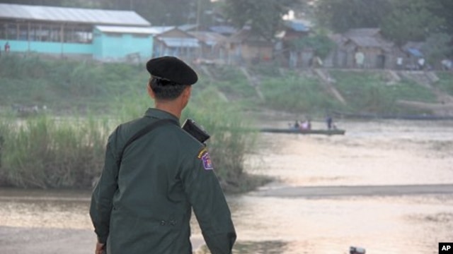 Thai soldier watches people who fled fighting take boats to and from Burma, Mae Sot, Thailand, 09 Nov 2010