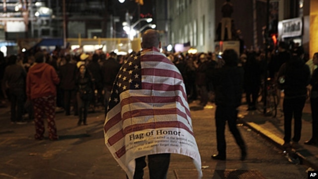 A man carries an American flag while walking to join a crowd gathered to celebrate the death of Osama bin Laden at the construction site at Ground Zero in New York, May 2, 2011.