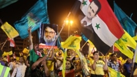 Hezbollah supporters wave flags and pictures of Syrian President Bashar al-Assad and Hezbollah leader Sheik Hassan Nasrallah during a rally marking the sixth anniversary of the 2006 Israel-Hezbollah war, in Beirut, July 18, 2012.