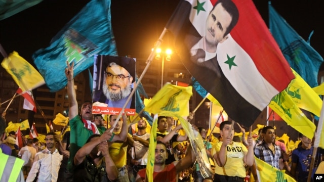 Hezbollah supporters wave flags and pictures of Syrian President Bashar al-Assad and Hezbollah leader Sheik Hassan Nasrallah during a rally marking the sixth anniversary of the 2006 Israel-Hezbollah war, in Beirut, July 18, 2012.