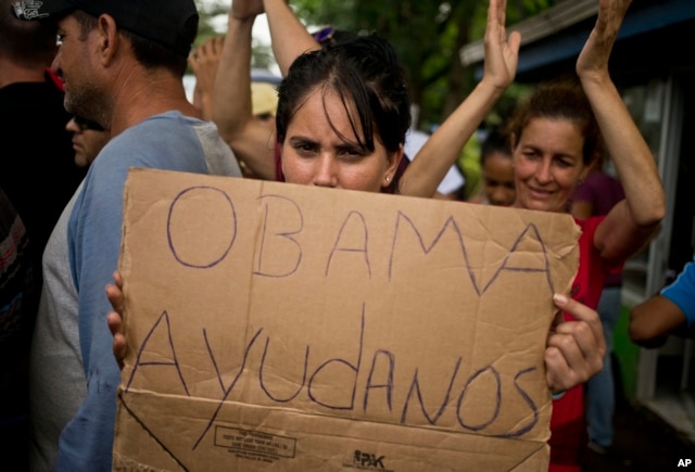 A Cuban migrant holds a sign that reads in Spanish "Help us Obama", Nov. 16, 2015.