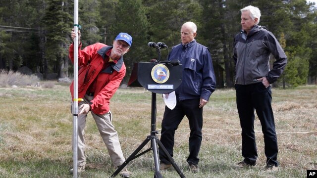 El gobernador de California, Jerry Brown (centro) observa hasta donde debería estar la nieve en las montañas de la Sierra Nevada.
