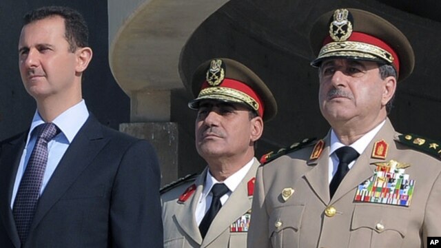 Chapdan prezident Bashar al-Assad, kimligi noma'lum harbiy va o'ngda, bugungi portlashda halok bo'lgan Mudofaa vaziri Dovud Rajha 