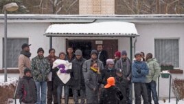 Asylum seekers stand outside an accommodation at a refugee holding centre in the town of Bad Belzig some 135 km (84 miles) south-west of Berlin, December 12, 2012.