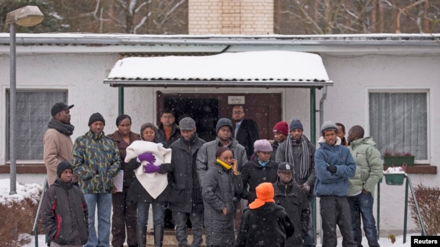 Asylum seekers stand outside an accommodation at a refugee holding centre in the town of Bad Belzig some 135 km (84 miles) south-west of Berlin, December 12, 2012.