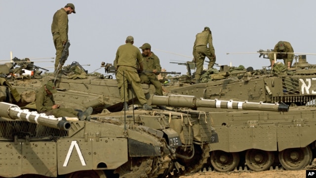 Israeli soldiers work on their a tanks in a staging ground in southern Israel, near the border with Gaza Strip, November 17, 2012. 
