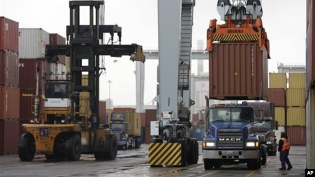 Driver watches as a freight container is lowered onto a tractor trailer by crane, Port of Boston, Dec. 18, 2012.